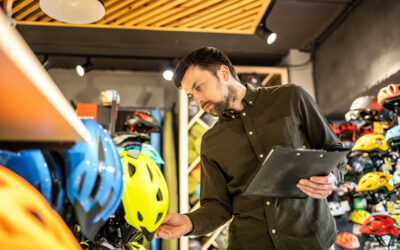 Bike shop manager makes an inventory of sports helmets in a bike shop.