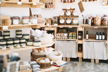 Wooden shelves with different food goods and personal hygiene or cosmetics products in grocery store.