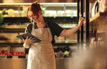 Female supermarket owner using a digital tablet to check inventory.