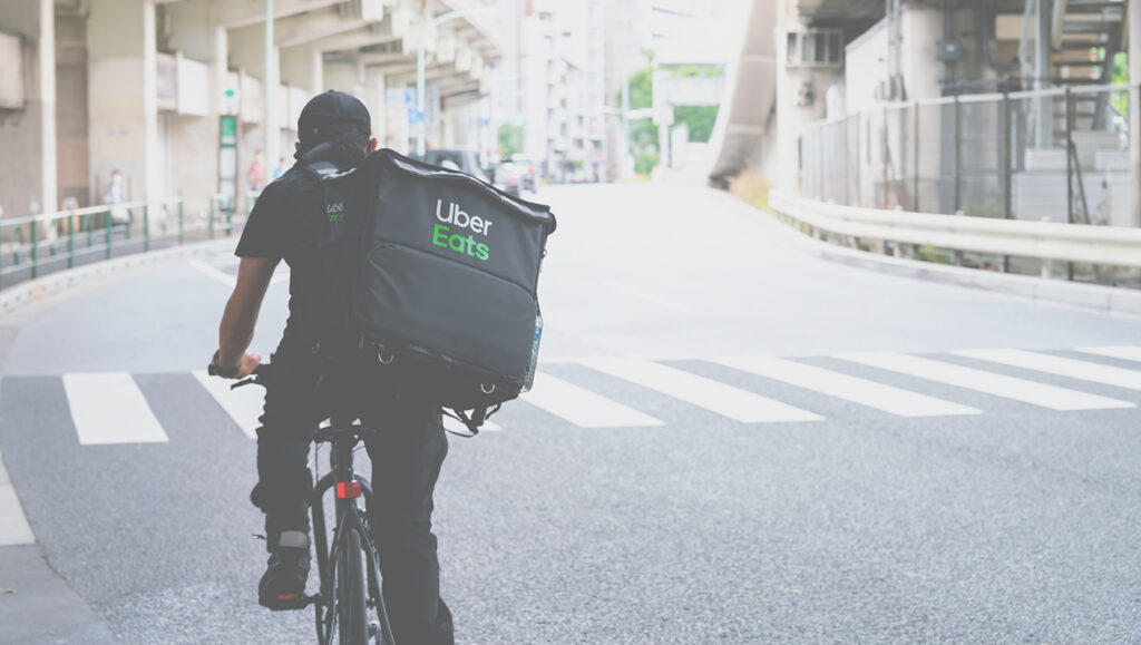 Uber Eats delivery bike rider on a bike riding down the street.