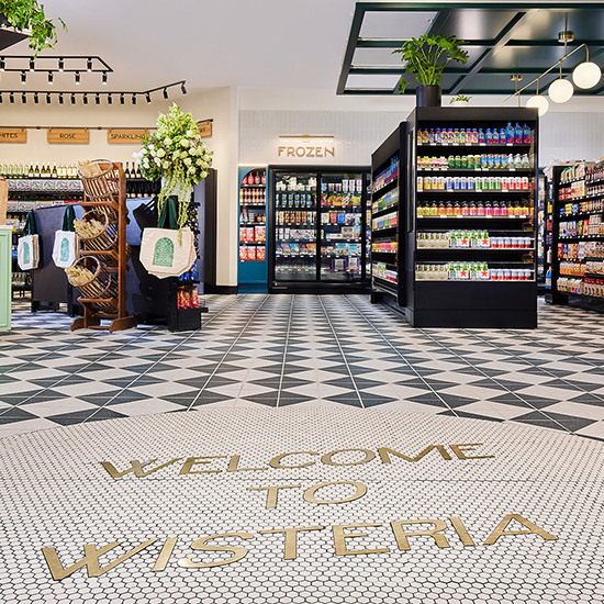 Welcome to Wisteria in floor tile with groceries in the background.