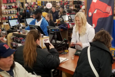 RCS employee helping a customer checkout at the Boston Red Sox team store. With NCR Counterpoint on the checkout screens in the background.