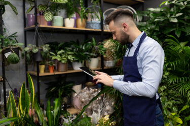 Man working in a garden center using a tablet to manage inventory.