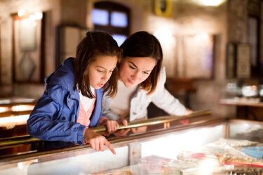 Mother and daughter exploring expositions of previous centuries in a museum