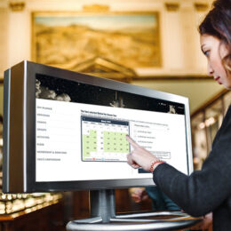 A woman in the museum uses the touchscreen monitor to purchase a ticket in Outbound.