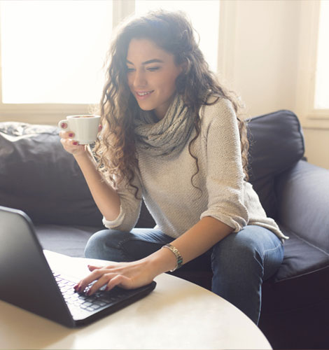 Woman sitting at home drinking coffee and shopping online.