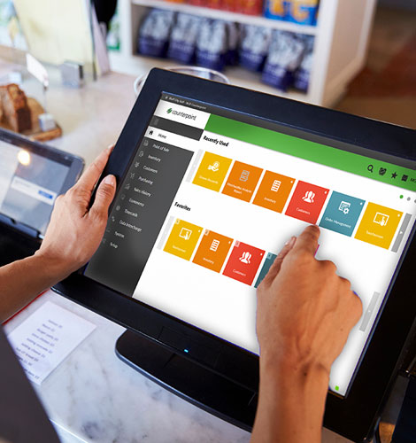 Retail associate using a touch screen point of sale register with NCR Counterpoint on the screen.