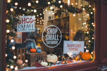 Unique holiday promotions in a small local gift shop. Festive Shop Small Saturday Window Display with Support Local Signs and Seasonal Decorations.