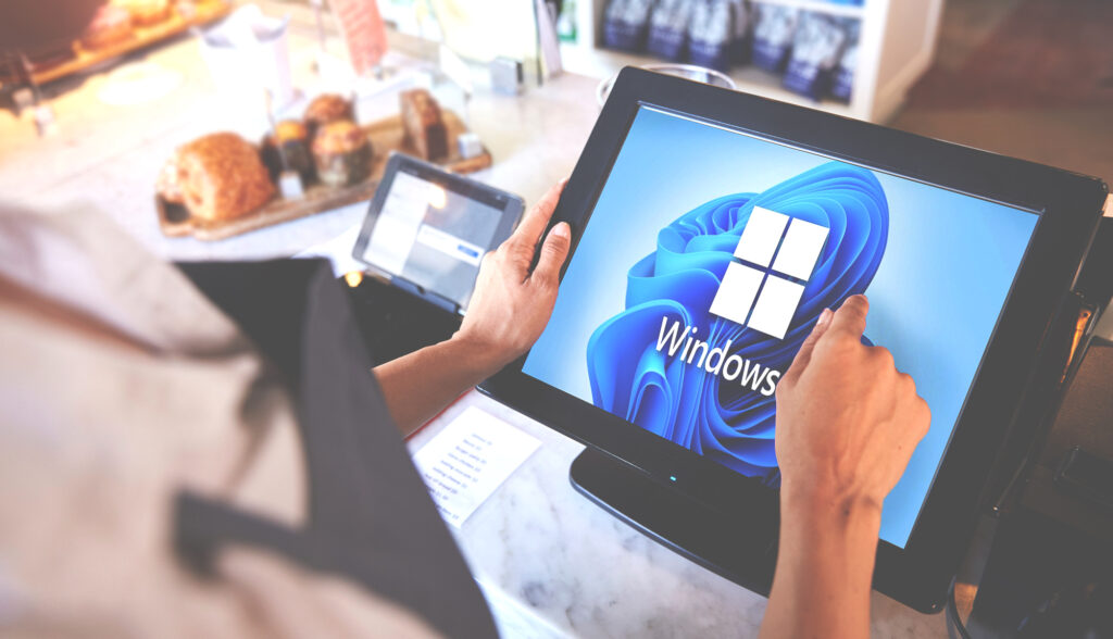 An employee looking at a point of sale monitor with a Windows 11 background on the display in a retail store.