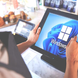 An employee looking at a point of sale monitor with a Windows 11 background on the display in a retail store.