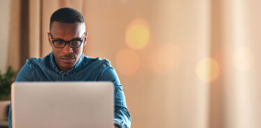 Business man looking at a laptop facing the camera.