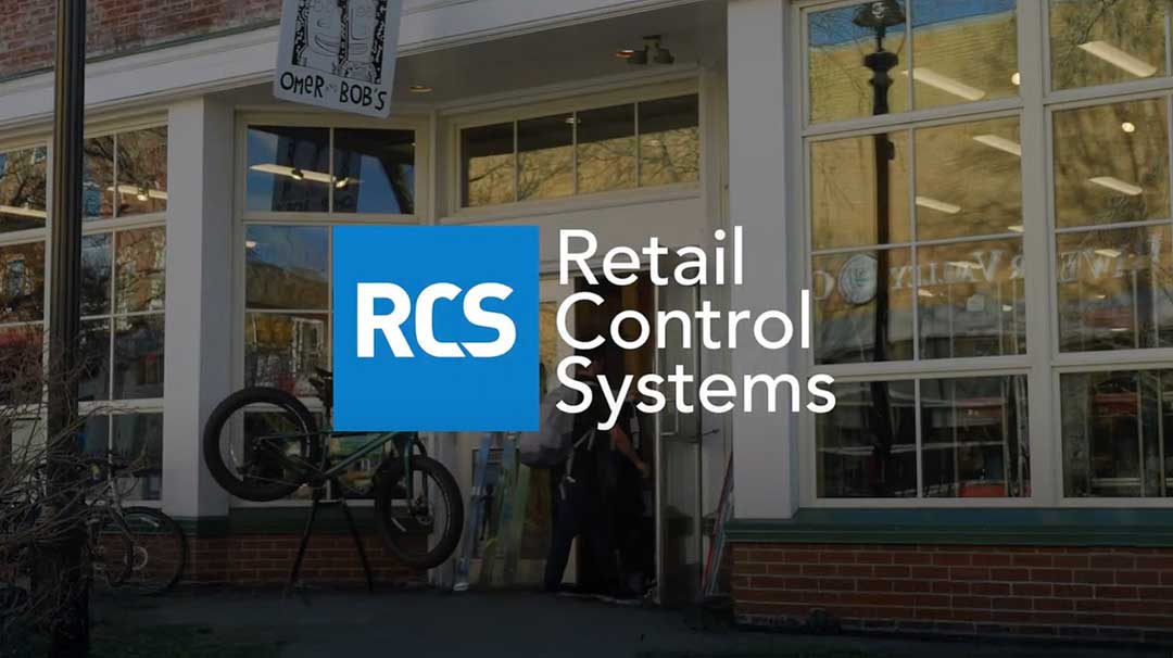 Video screenshot of the RCS Mission video. The Retail Control Systems logo is on the center of the screen and someone is walking into a sporting goods retail store.