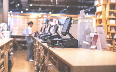 Retail employee standing at the end of a long line of registers. The registers all have security features installed to prevent cybersecurity threats.