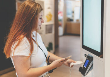 Woman getting her receipt at a self checkout kiosk.